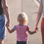 Free parent holding child's hand